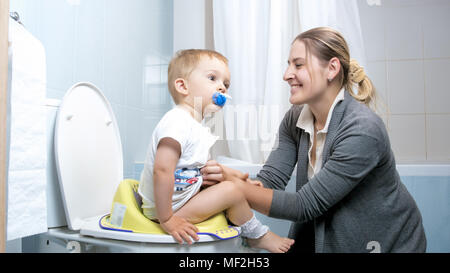 Cute Baby boy sitting besondere Kinder Sitz auf der Toilette Stockfoto