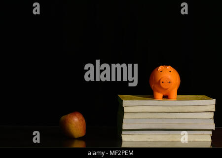 Sparschwein auf Buch gegen Blackboard Stockfoto