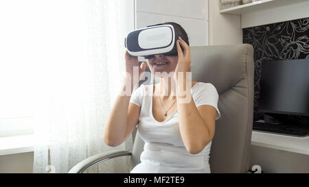 Portrait von lächelnden jungen Frau ansehen Film in VR-Headset Stockfoto