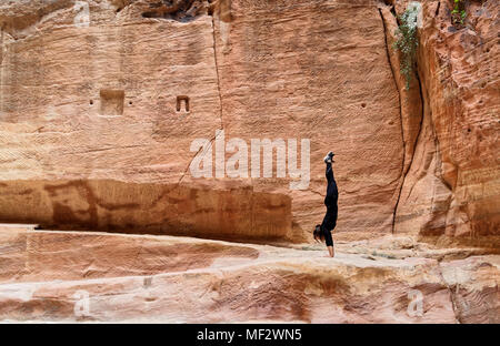 Petra, Wadi Musa, Jordanien, 9. März 2018: Junge Europäische Mädchen Training einen Handstand im siq von Petra, Naher Osten Stockfoto