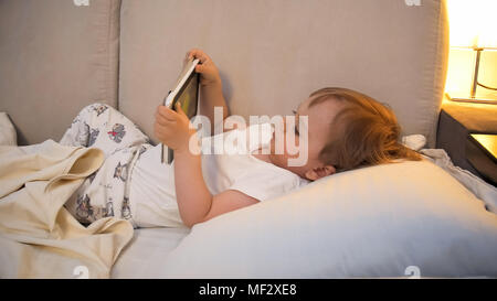 Portrait von niedlichen toddler Boy mit digitalen Tablette nachts im Bett Stockfoto