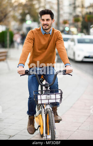 Spanien, Andalusien, Granada. Hübscher junger Mann auf dem Fahrrad in der Stadt. Lifestyle Konzept. Stockfoto