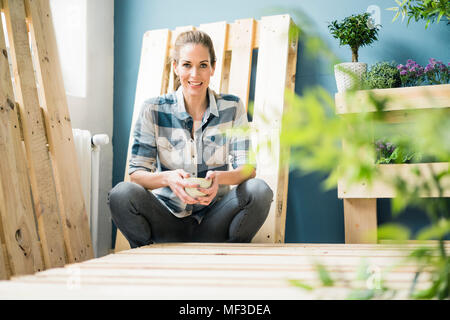 Schöne Frau eine Pause von einer Renovierung Ihrer Wohnung mit Paletten, trinken Kaffee Stockfoto