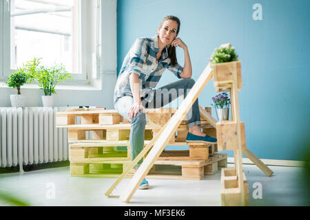 Schöne Frau ihr Haus renoviert mit Paletten Stockfoto