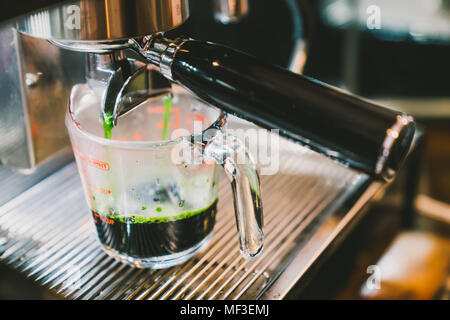 Barista heiße Grüner Tee mit Kaffeemaschine Maschine, close-up auf der Skala messen Glas. Cafe Lifestyle, Essen und Trinken Small Business Konzept Stockfoto