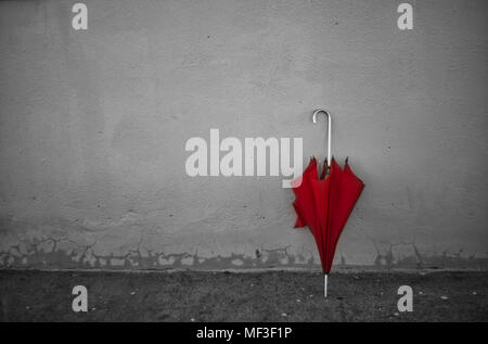 Vintage rot Regenschirm lehnte sich auf eine graue Wand. Stockfoto