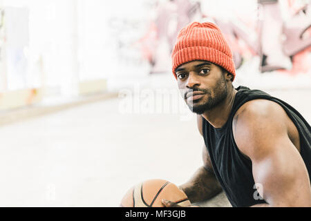 Mann mit Tattoos und Wollmütze holding Basketball Stockfoto