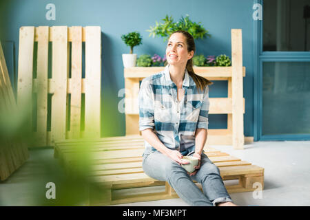 Schöne Frau eine Pause von einer Renovierung Ihrer Wohnung mit Paletten, trinken Kaffee Stockfoto