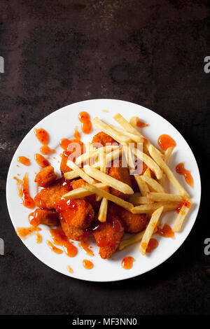 Platte von Chicken Nuggets mit Sweet Chili Sauce und Pommes Frites auf Dark Metal Stockfoto