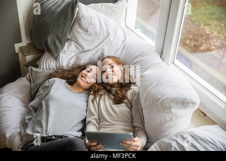 Zwei glückliche Mädchen im Teenageralter Entspannung mit der Tablette zu Hause Stockfoto