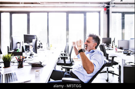 Gerne reife Geschäftsmann Jubel am Schreibtisch im Büro Stockfoto