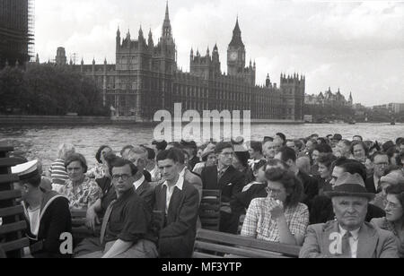 1950er, historisches Bild aus dieser Zeit einer Gruppe von Menschen auf einem Boot sitzen und eine Flussfahrt entlang der Themse genießen, während sie am ikonischen Londoner Gebäude, dem Palace of Westminster, den britischen Houses of Parliament, der Regierung des Vereinigten Königreichs im Hintergrund vorbeigehen. Stockfoto