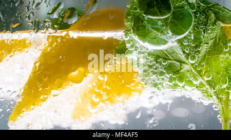 Nahaufnahme von Luftblasen auf zitronenscheiben und Minze und Glas Limonade Stockfoto