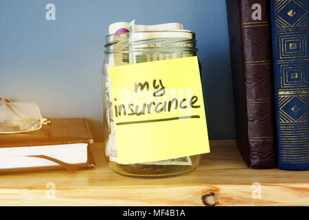 Glas mit meiner Versicherung und Bargeld im Inneren unterzeichnen. Stockfoto