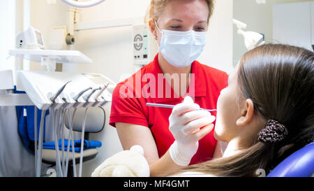 Portrait von weiblichen pädiatrischer Zahnarzt Inspektion Mädchen Zähne Zahnarzt Stuhl Stockfoto