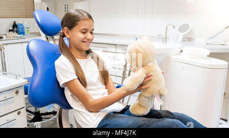 Porträt der lächelnde niedliche Mädchen spielen mit Teddybär in der Zahnarztpraxis Stockfoto