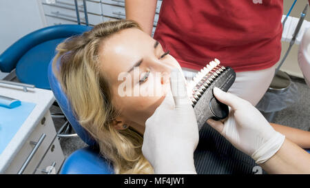 Closeup Bild von Zahnarzt in Latex Handschuhe holding Zähne Farbton Proben bei Patienten Zähne Stockfoto