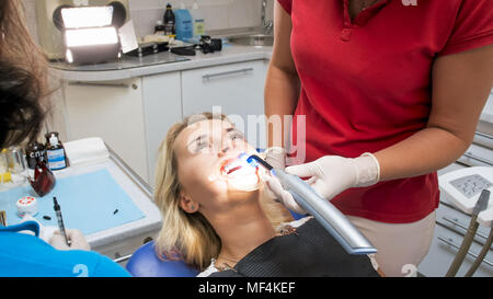 Closeup Portrait von Zahnarzt assistant Holding UV-Lampe bei Patienten Mund Stockfoto