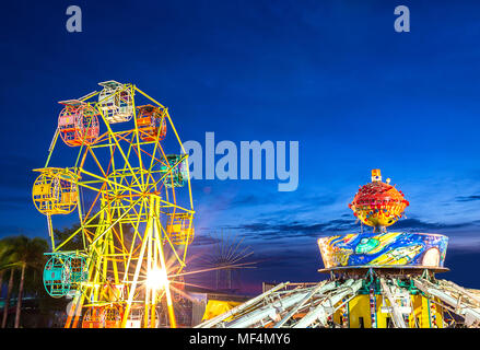 Riesenrad und die schwere Maschine in beweglichen Vergnügungspark bei Sonnenuntergang Zeit in Thailand. Stockfoto