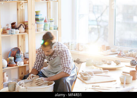 Junge konzentriert gemischten Rennen Handwerker, Steingut auf Keramik Rad in der Werkstatt durch helles Sonnenlicht beleuchtet Stockfoto
