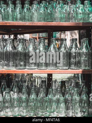 Viele vintage transparenten Glasflaschen auf drei Regale Stockfoto