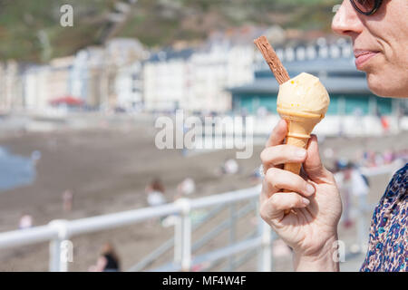 Essen, Eis, mit, Flake, auf, unseasonally, warm, April, Sommer, wie, Temperaturen, Aberystwyth, Promenade, sonnig, blau, Himmel, Samstag, Ceredigion, Wales, Welsh, Stockfoto