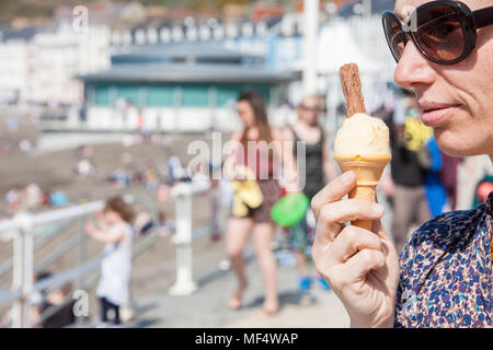 Essen, Eis, mit, Flake, auf, unseasonally, warm, April, Sommer, wie, Temperaturen, Aberystwyth, Promenade, sonnig, blau, Himmel, Samstag, Ceredigion, Wales, Welsh, Stockfoto