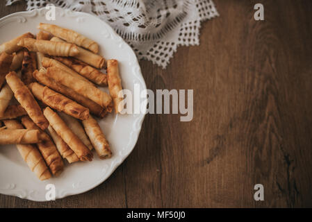 Türkische Zigarette patty auf weiße Platte und Holztisch. Stockfoto