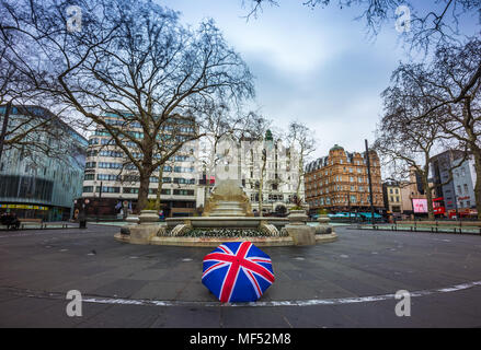 London, England - 03.18.2018: Iconic Union Jack Regenschirm am Leicester Square mit der Statue von William Shakespeare an einem bewölkten Morgen Stockfoto