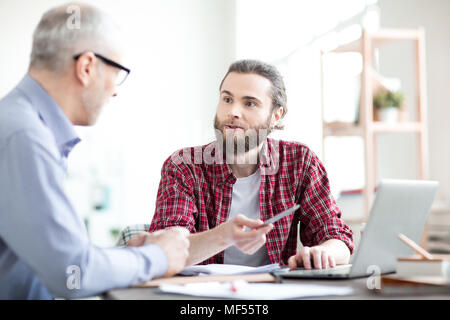 Business Kollegen am Tisch sitzen und mit Laptop zusammen im Team Stockfoto