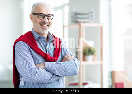 Portrait von Reifen executive Stand mit verschränkten Armen und lächelnd Stockfoto