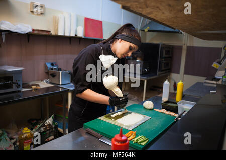 Frau in Schwarz Küchenchef bereitet Sushi Restaurant. Stockfoto