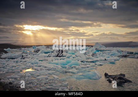 Island, südlich von Island, Joekulsarlon Glacier Lake, Eisberge und Sonnenschein durch Wolken Stockfoto