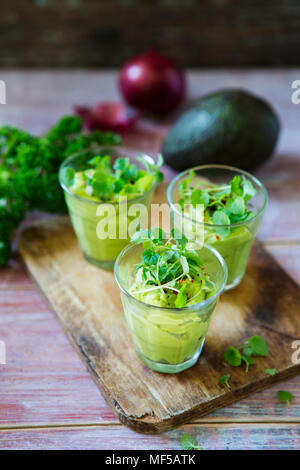 Gläser Avocadocreme mit Chili Flocken, Kresse und Petersilie Stockfoto