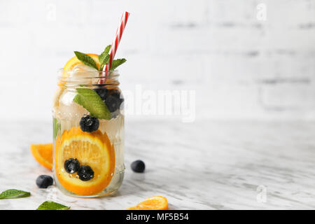 Glas infundiert Wasser mit Orange, Blaubeeren und Minze auf Eis Stockfoto