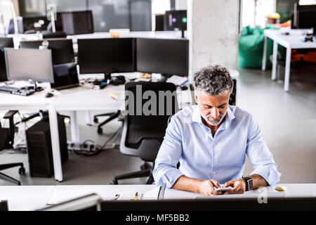 Reifen Geschäftsmann am Schreibtisch im Büro mit Smartphone Stockfoto