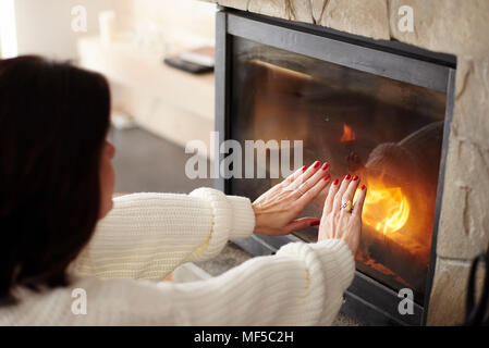 Reife Frau Erwärmung die Hände am Kamin Stockfoto