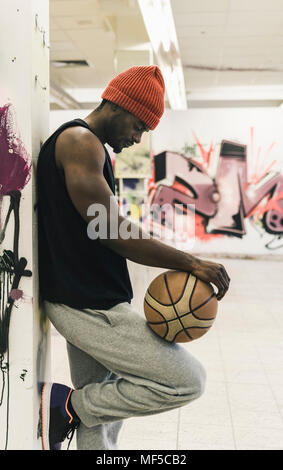 Mann mit Tattoos und Wollmütze holding Basketball Stockfoto