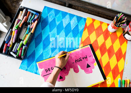 Artist's Hand Zeichnung in Notebook mit seinem Kunstwerk auf dem Tisch Stockfoto