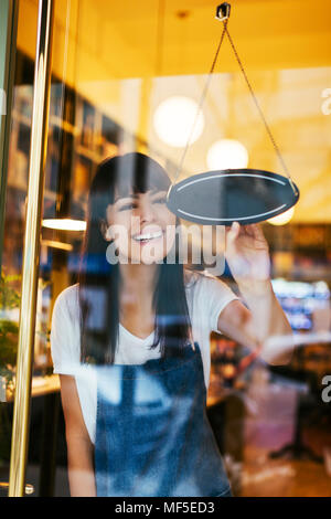 Glückliche Frau drehen Anmelden Fenster eines Store Stockfoto