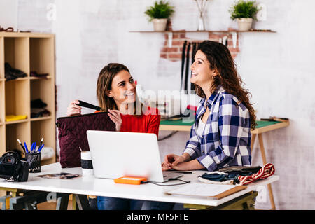 Zwei lächelnde Fashion Designer im Studio mit Laptop Stockfoto