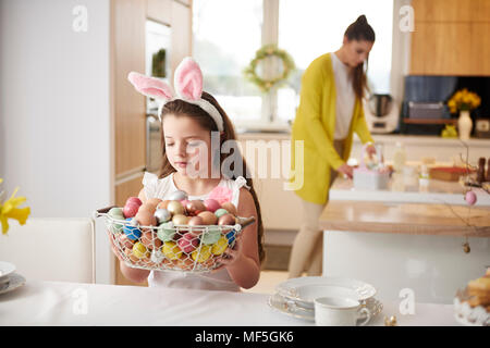 Mädchen Inverkehrbringen Korb voller Ostereier auf Esstisch Stockfoto