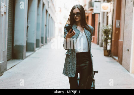 Junge Geschäftsfrau in der Stadt prüfen Handy Stockfoto