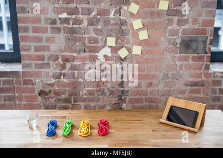 Tablet und Reihe der farbigen Stromkabel auf hölzernen Tisch Stockfoto