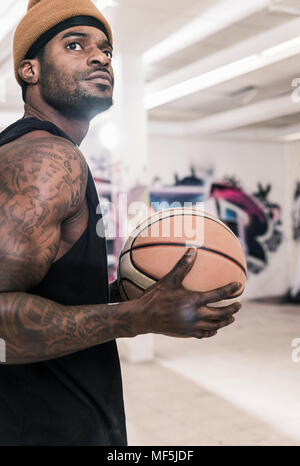 Mann mit Tattoos und Wollmütze holding Basketball Stockfoto