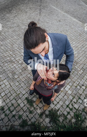 Unternehmer stehen auf Kopfsteinpflaster bei Frau suchen mit der Hand auf ihren Schultern Stockfoto