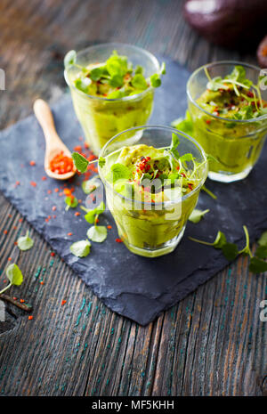 Gläser Avocadocreme mit Chili Flocken, Kresse und Petersilie Stockfoto