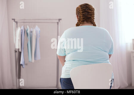 Stout junge Frau sitzt auf dem Stuhl Stockfoto