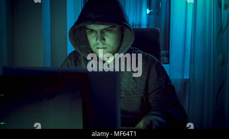 Junge Hacker in hoodie Arbeiten am Computer in der Nacht Stockfoto