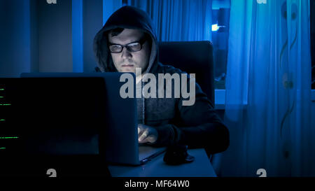 Junge konzentriert Mann in Brillen auf Laptop in der Nacht arbeiten Stockfoto